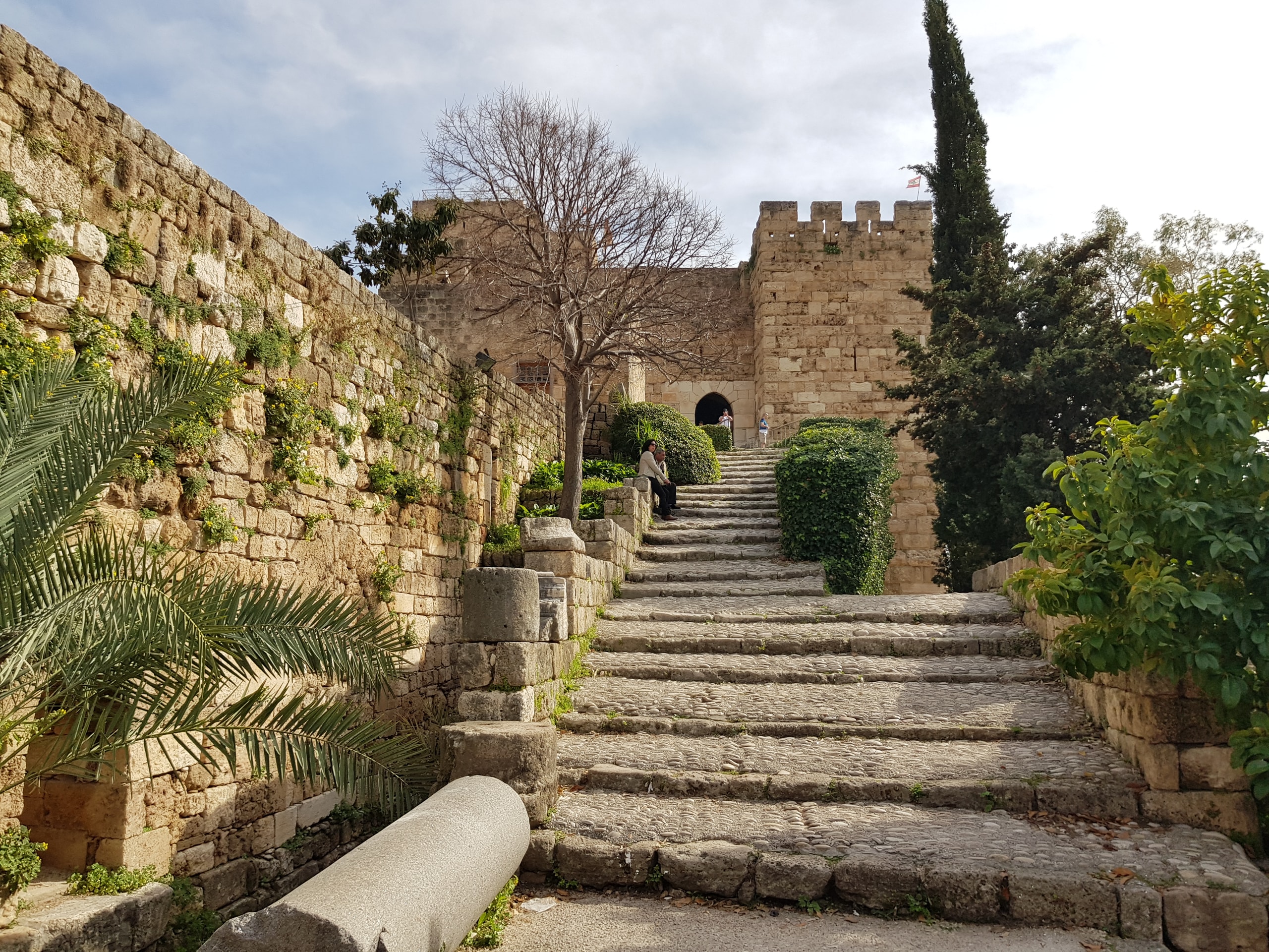 Stone steps climbing between old walls toward a crenellated castle gate