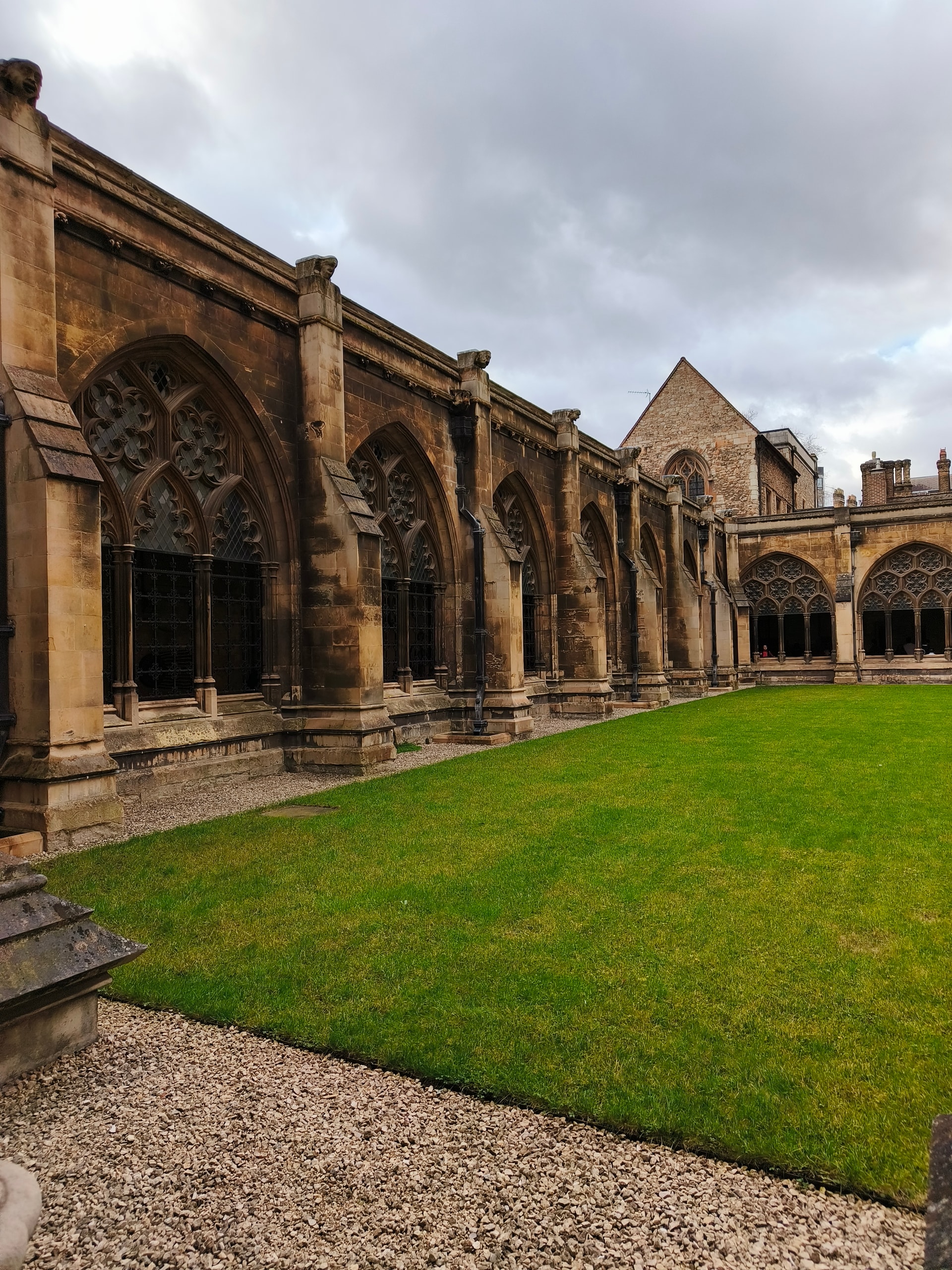 Gothic cloister with stone arcades wrapped around a bright green lawn