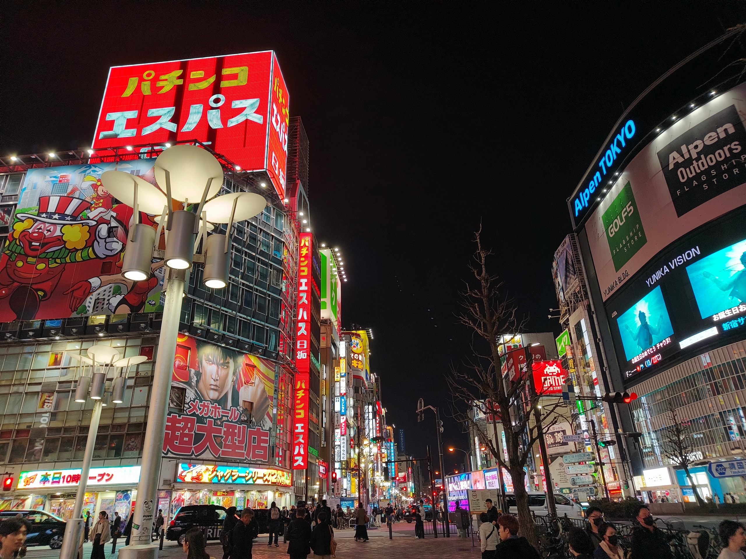 Neon signs and lit billboards over a busy city street at night