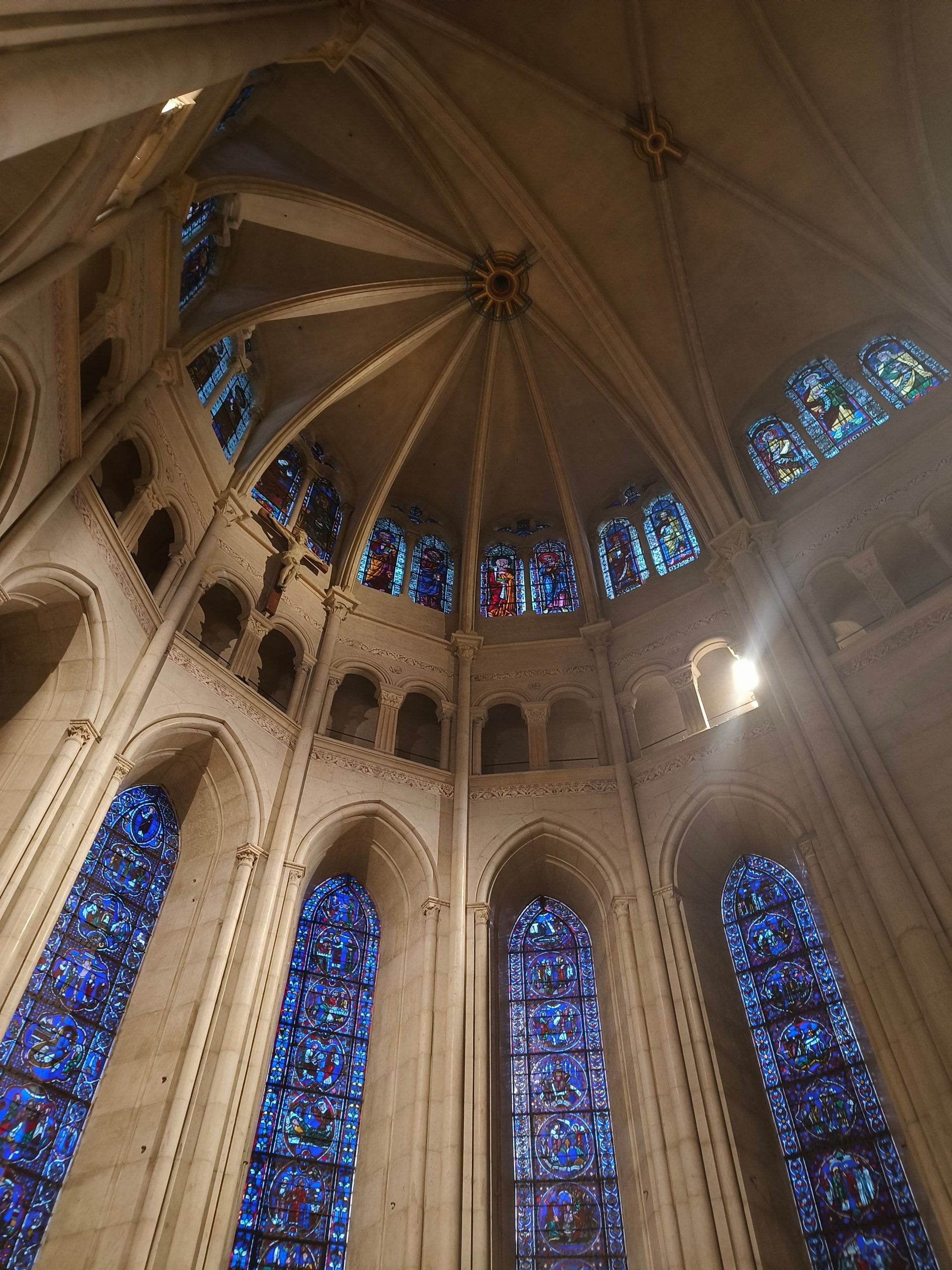 Looking straight up into a vaulted apse lined with tall blue stained-glass windows