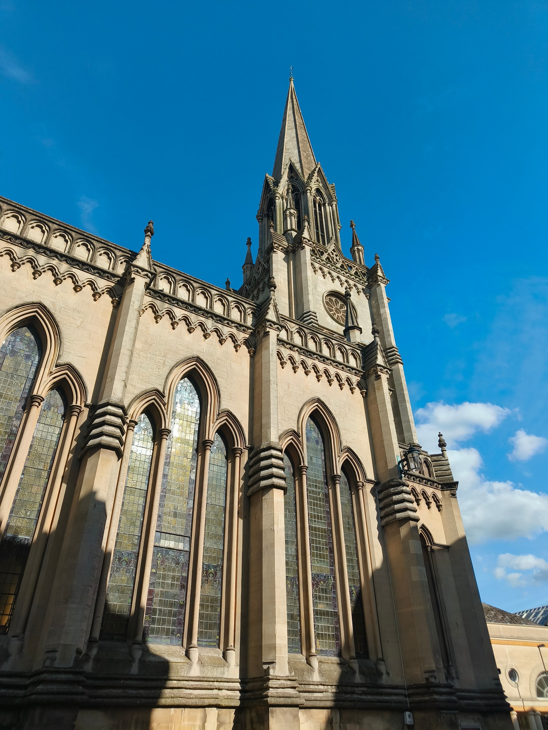 Gothic church spire and pinnacled stone facade against a clear blue sky