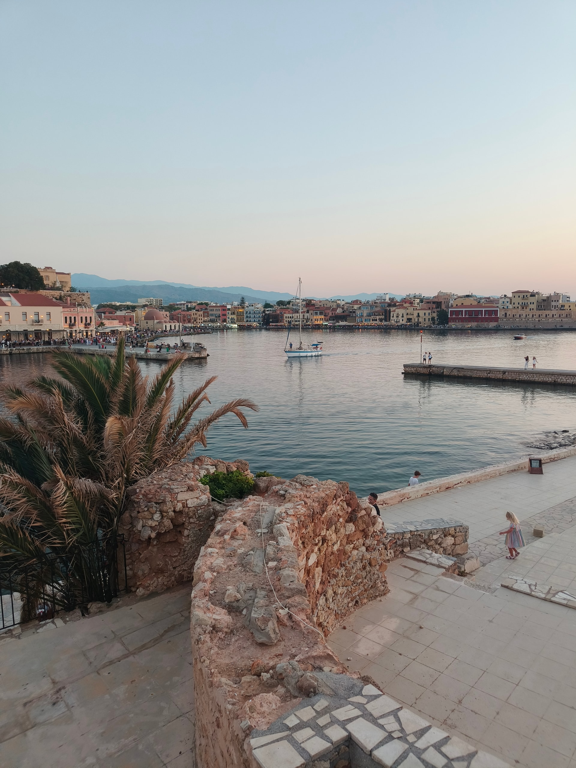 Harbour town at dusk with boats, palms and old stone walls