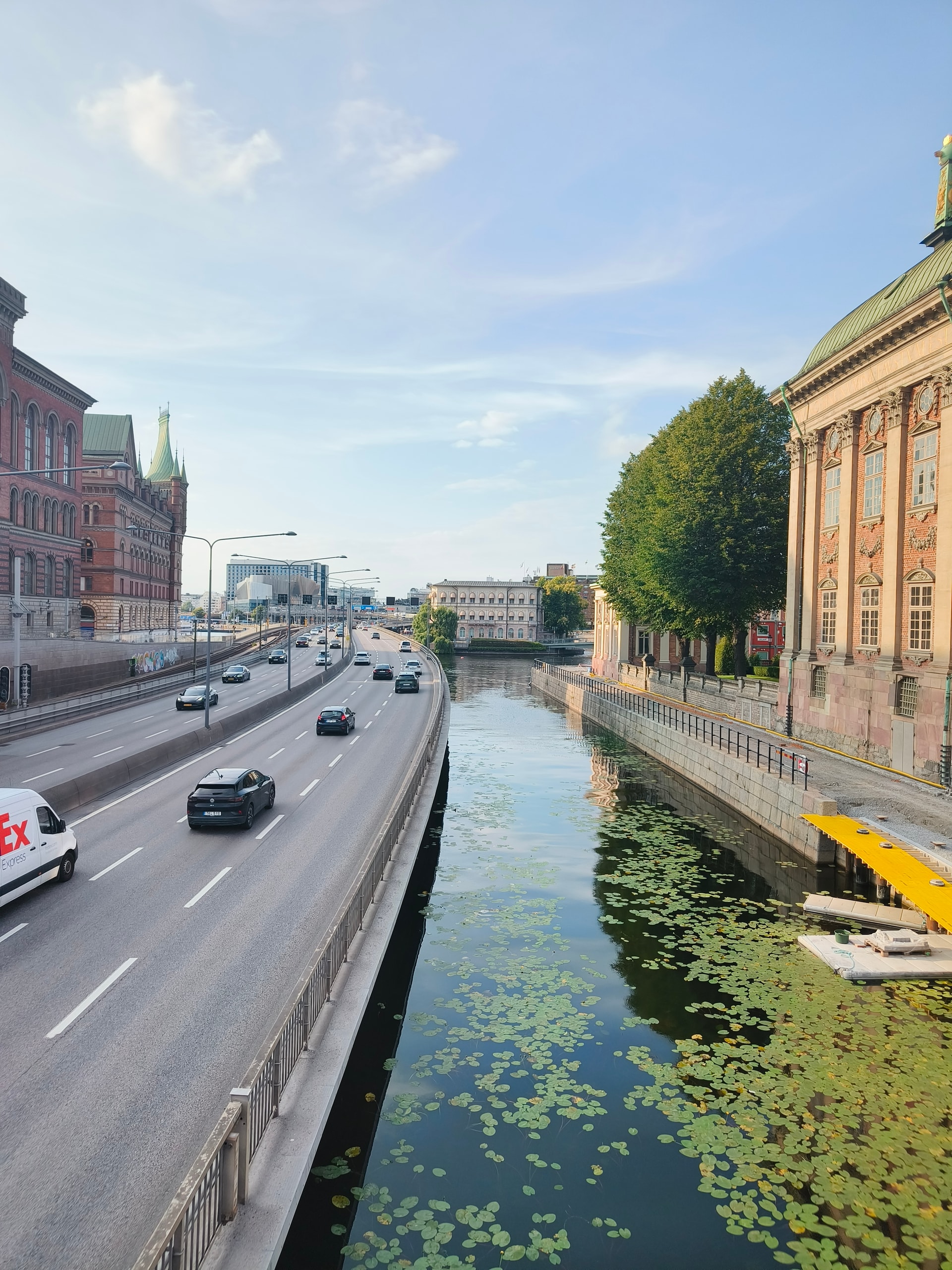 City road running alongside a tree-lined canal and grand stone buildings