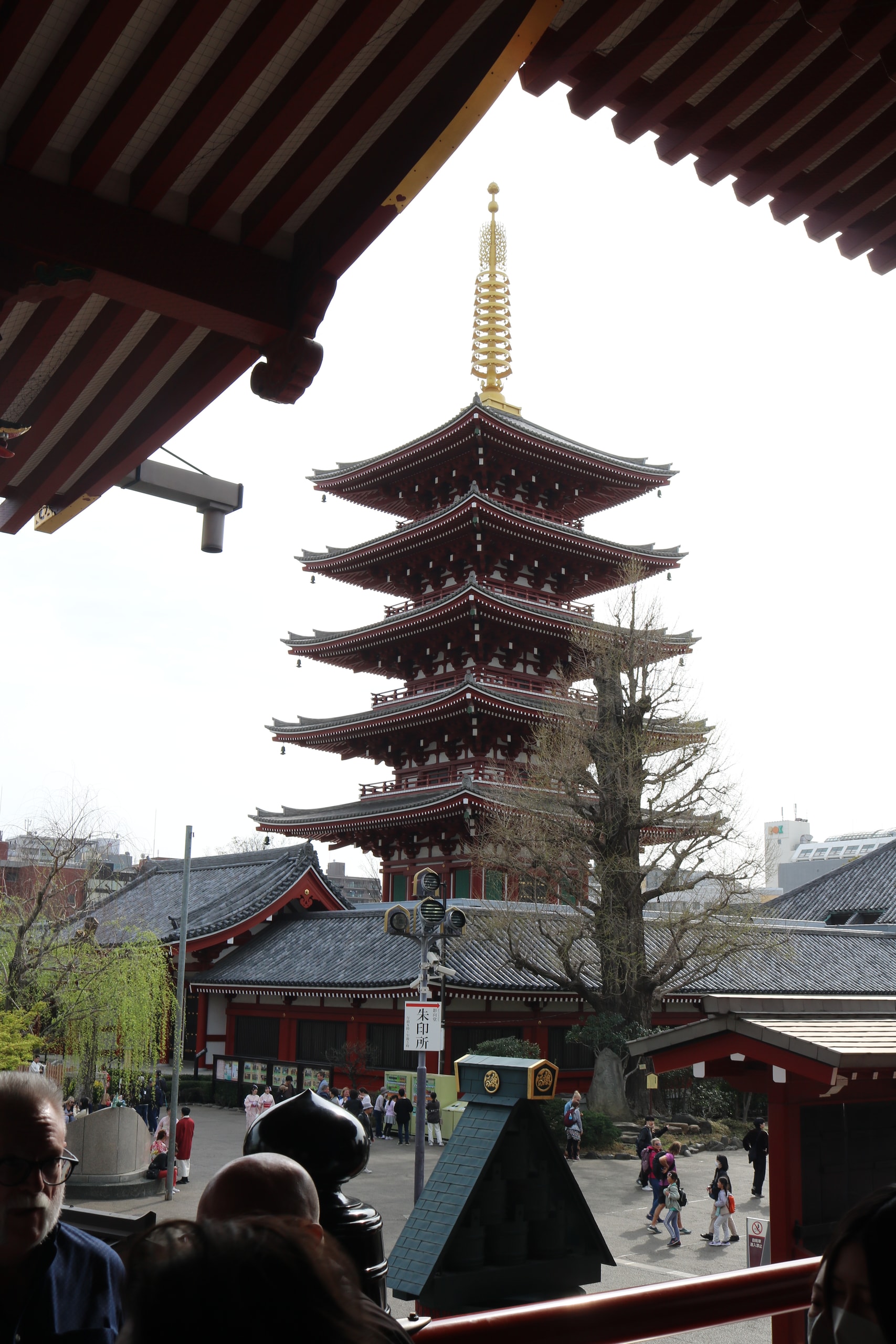 Five-storey pagoda framed by a temple roof above a crowded courtyard