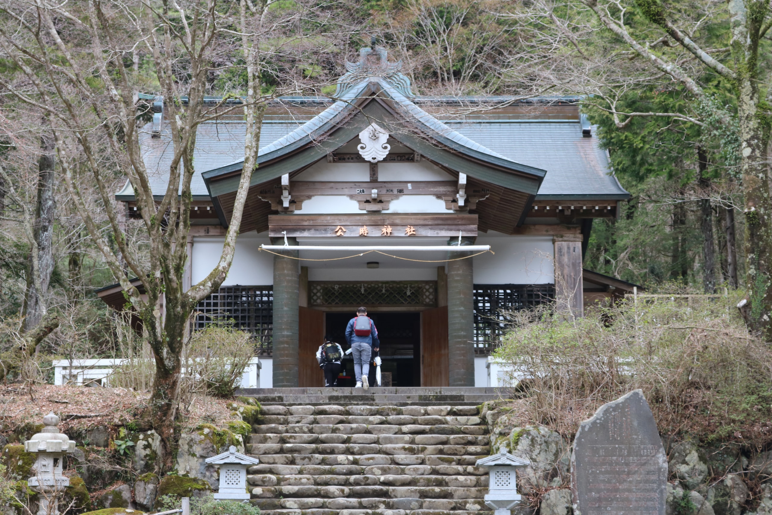 Small shrine at the top of stone steps among bare winter trees