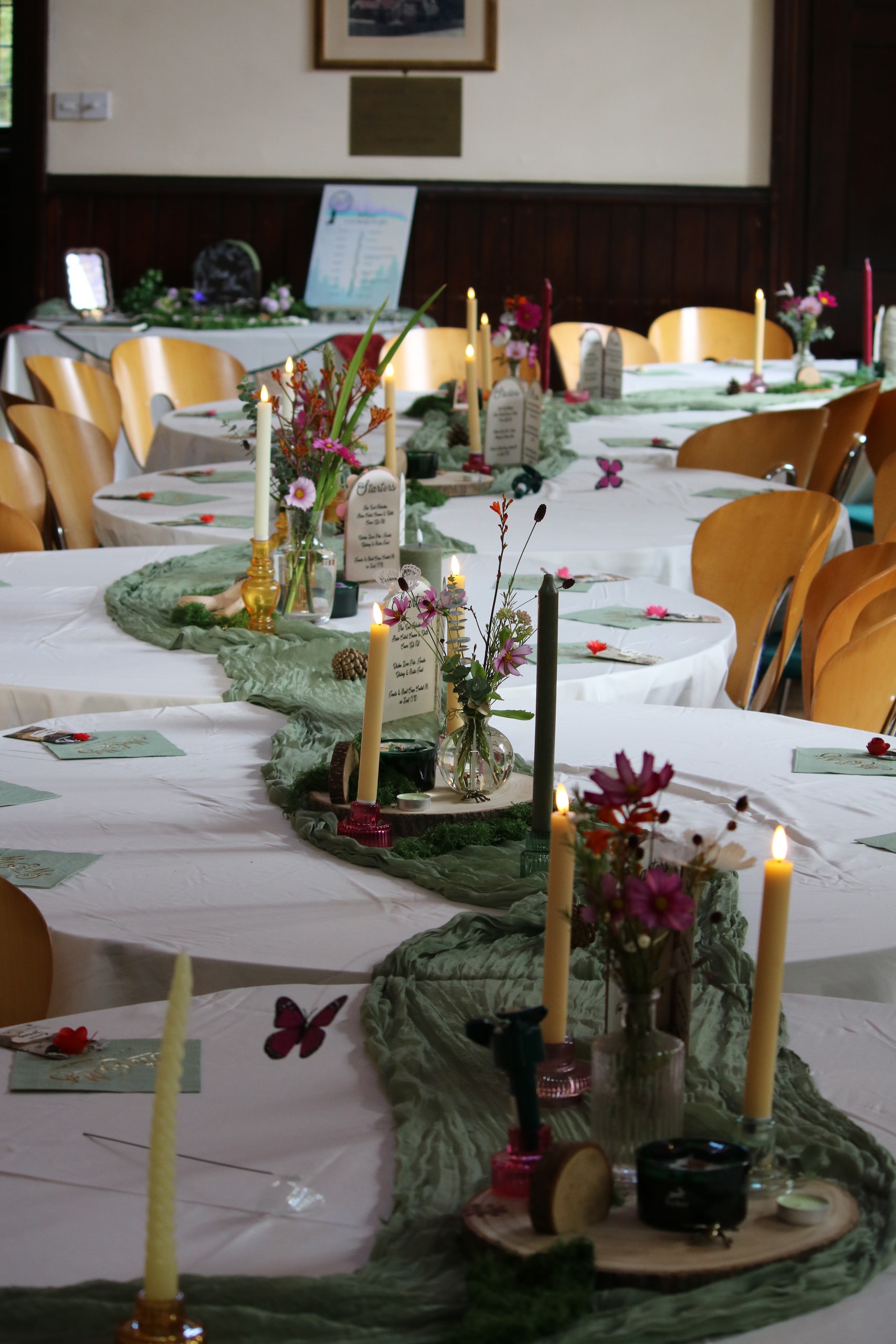 Long view down tables laid with green runners, candles and wildflowers