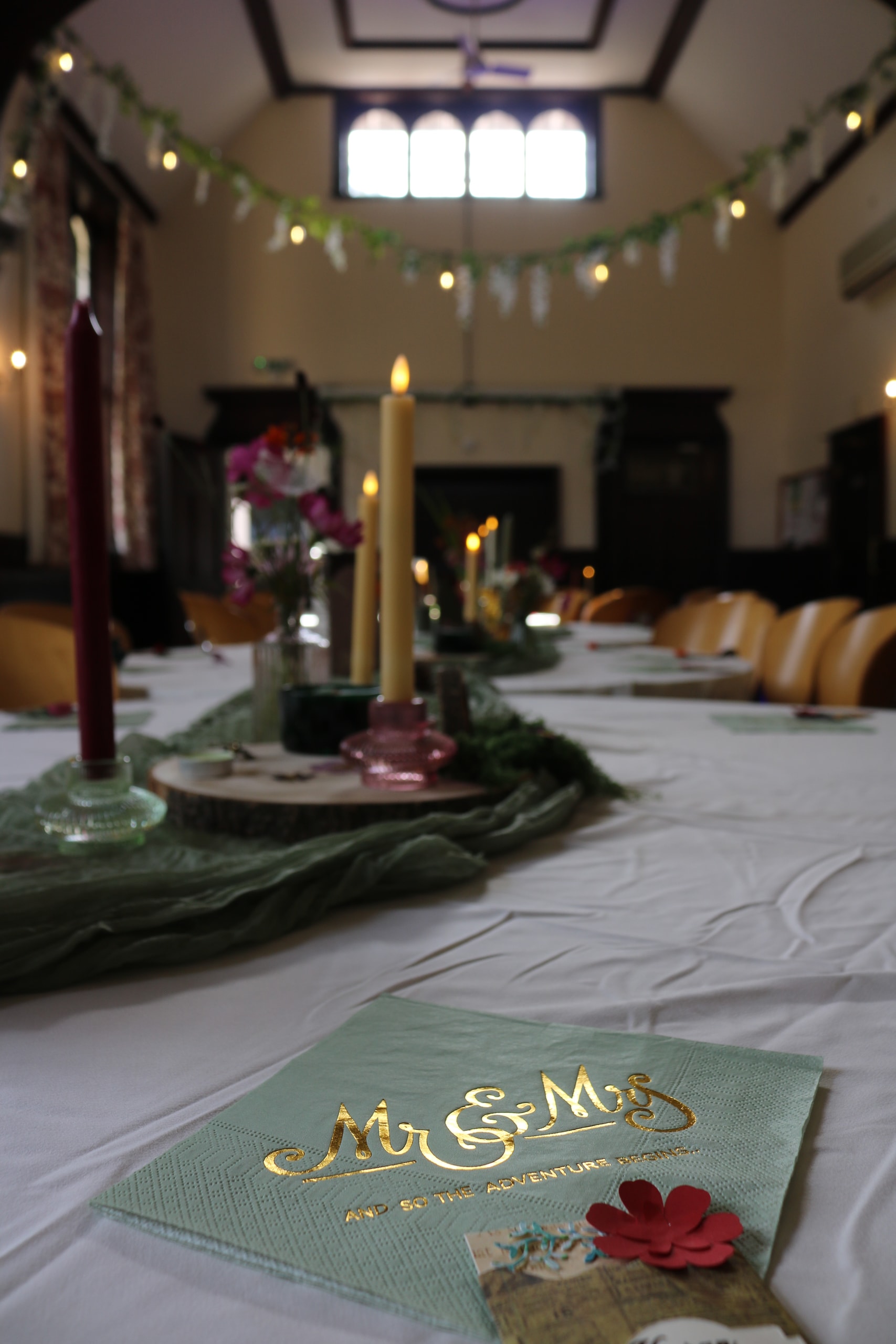 Place setting with a gold Mr and Mrs card beside candles and a table runner
