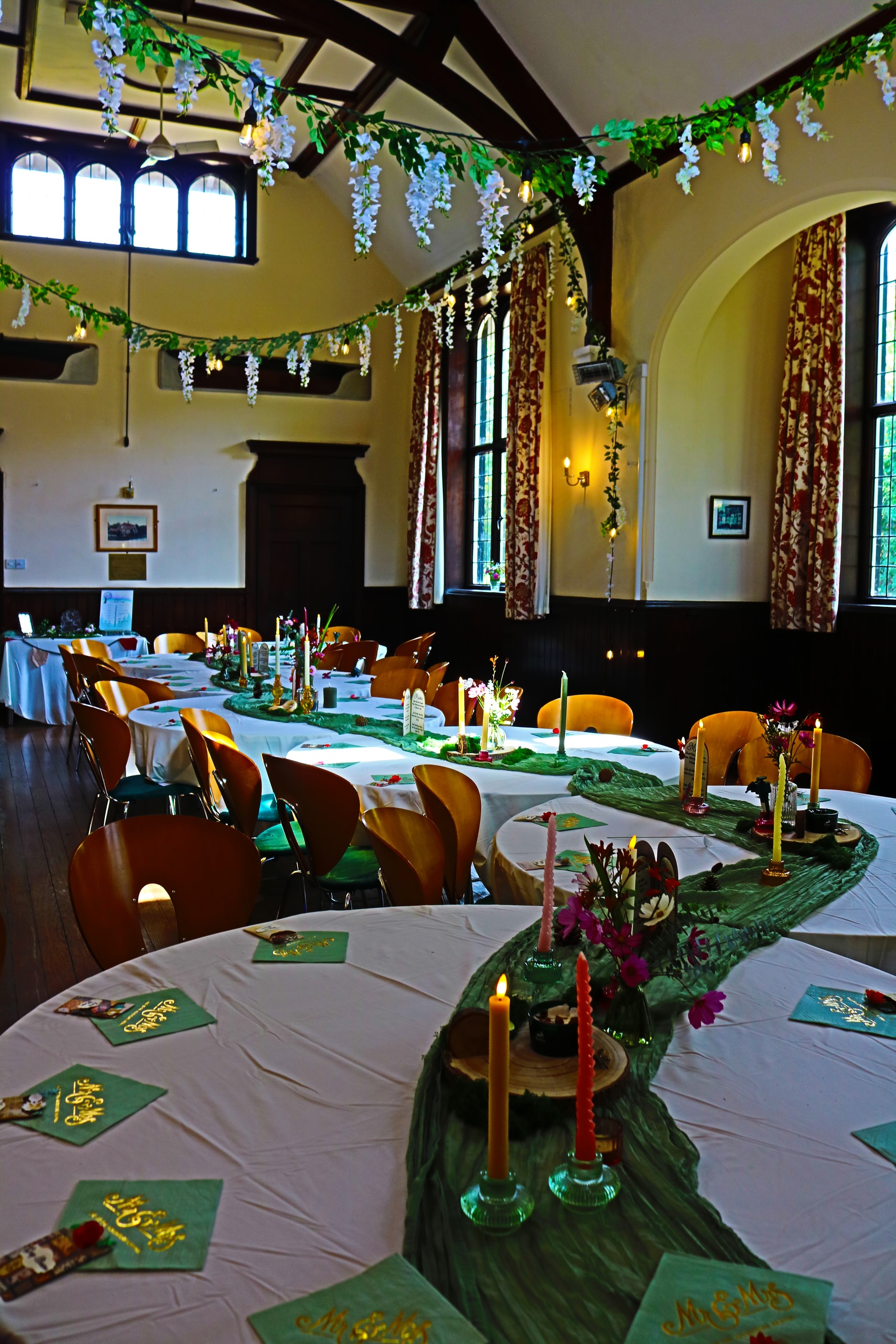 Reception hall from above, round tables and garlands beneath wooden beams