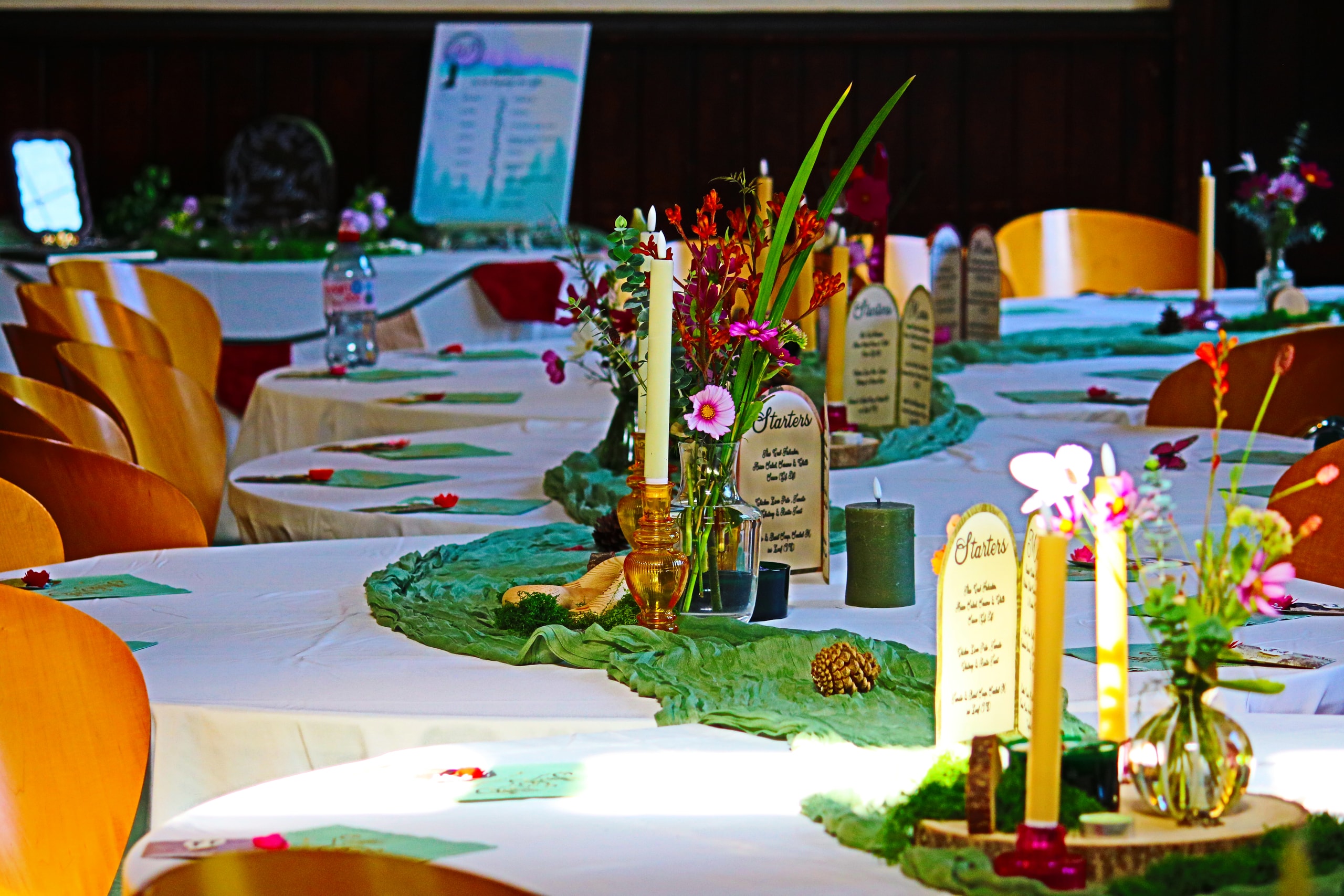 Candles, wildflowers and name cards along a table with a green runner