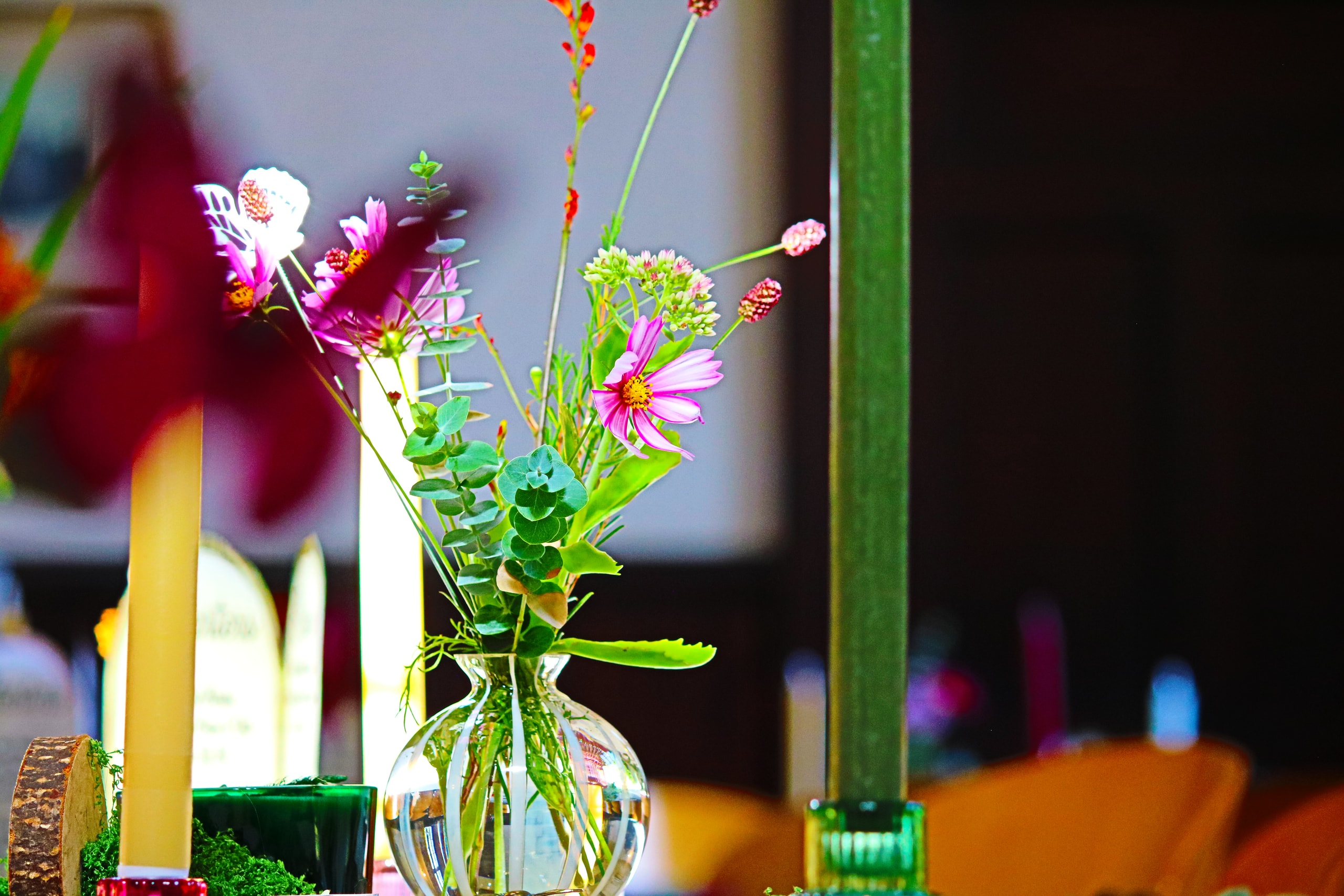 Close-up of wildflowers in a small glass vase beside candles