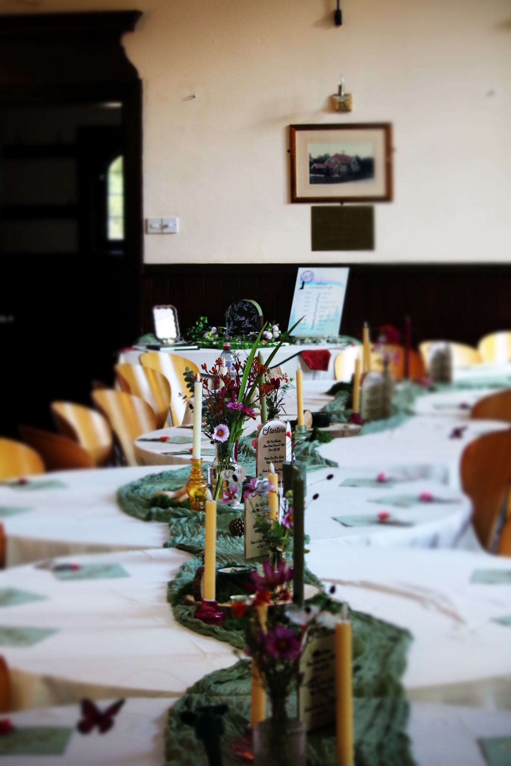 Candlelit tables leading toward a framed picture on the far wall